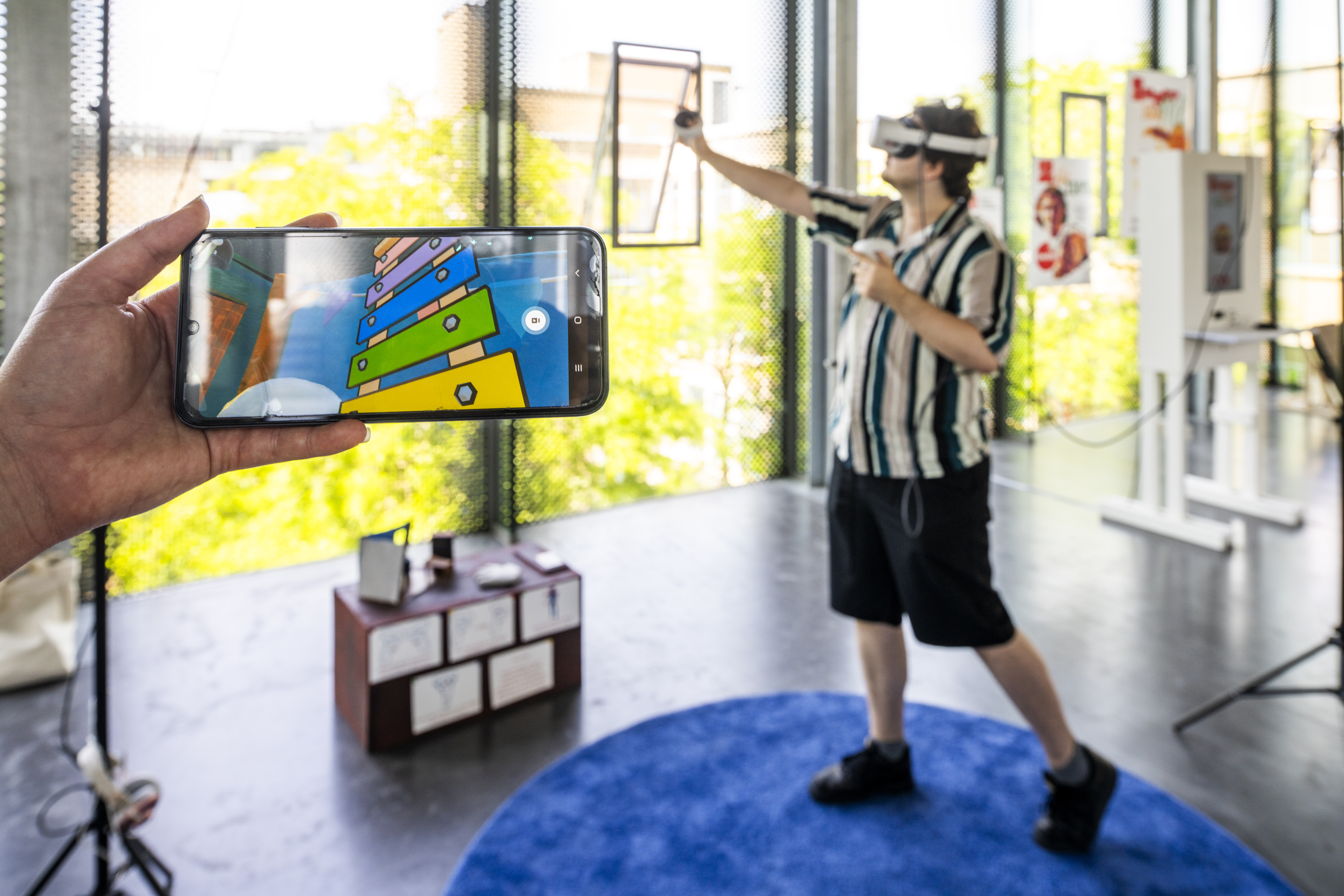 A participant playing while the in-game view is shown on a phone